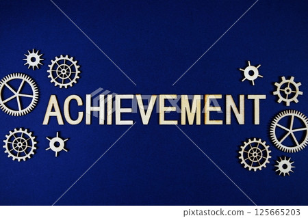 Achievement alphabet letters with gears element on navy blue background 125665203