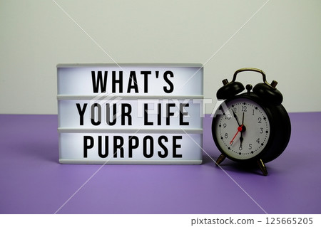 What Is Your Life Purpose? text on light box with alarm clock on purple background What Is Your Life Purpose? text on light box with alarm clock on purple background 125665205