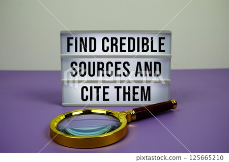 Find Credible Sources And Cite Them text on light box with magnifying glass on purple background 125665210