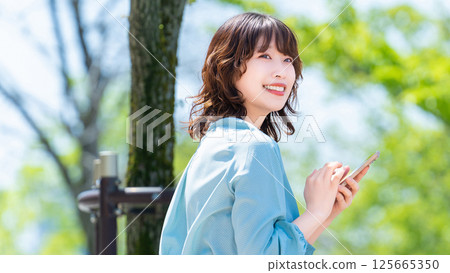 在戶外使用智慧型手機的微笑女性/女商人 125665350