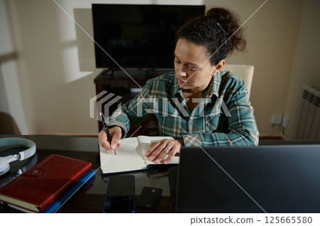 Focused Woman Writing Notes While Working from Home, Focused Woman Writing Notes While Working from Home, 125665580