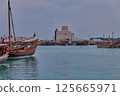 Museum of Islamic Art in Doha, Qatar daylight view with Dhows in Arabic gulf with Qatar flag in foreground Museum of Islamic Art in Doha, Qatar daylight view with Dhows in Arabic gulf with Qatar flag in foreground 125665971