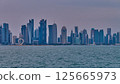 Doha Qatar skyline from corniche promenade sunset shot showing dhows in Arabic gulf with Qatar flag Doha Qatar skyline from corniche promenade sunset shot showing dhows in Arabic gulf with Qatar flag 125665973