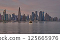 Doha Qatar skyline from corniche promenade sunset shot showing dhows in Arabic gulf with Qatar flag Doha Qatar skyline from corniche promenade sunset shot showing dhows in Arabic gulf with Qatar flag 125665976