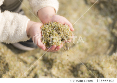孩子手中收集的閃閃發光的玻璃沙 125666308