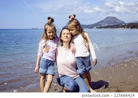 mother with twins daughters on beach 125666424