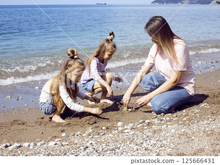 mother with twins daughters on beach mother with twins daughters on beach 125666431