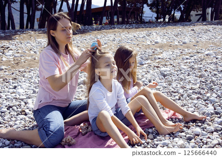 mother with twins daughters on beach 125666440