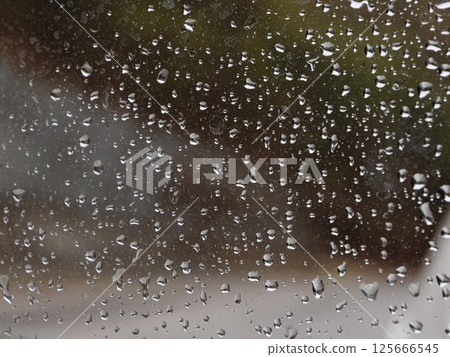 Raindrops cascading down glass surface, forming delicate, translucent streams during wet weather condition Raindrops cascading down glass surface, forming delicate, translucent streams during wet weather condition 125666545