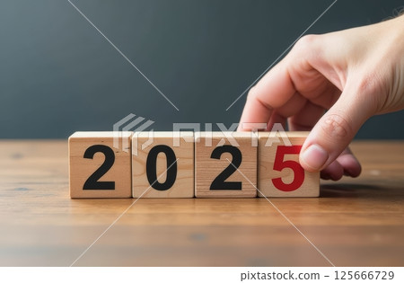Hand touching wooden cubes with 2025 numbers. New Year concept for Business, future planning. 125666729