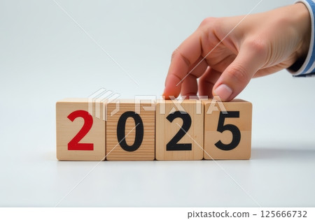 Hand touching wooden cubes with 2025 numbers. New Year concept for Business, future planning. 125666732