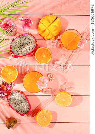 Summer party concept. Sunny tropical flyer, background with cocktails and juices from citrus, dragon fruit and mango. Exotic fruits and orchid flowers on a bright background. Business card for a bar 125666978
