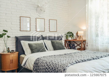 Stylish interior of bedroom with big comfortable grey bed Stylish interior of bedroom with big comfortable grey bed 125667075