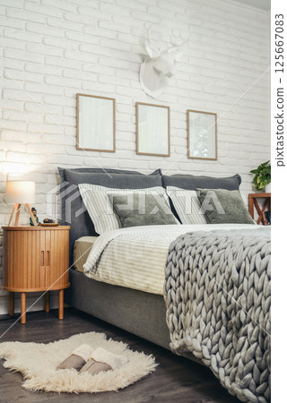 Stylish interior of bedroom with big comfortable grey bed Stylish interior of bedroom with big comfortable grey bed 125667083