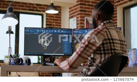 African american industrial designer works on prototypes in a creative studio. Doing tech driven remote work with 3D modeling and CAD software, industrial tools for technical precision. Camera B. African american industrial designer works on prototypes in a creative studio. Doing tech driven remote work with 3D modeling and CAD software, industrial tools for technical precision. Camera B. 125667874