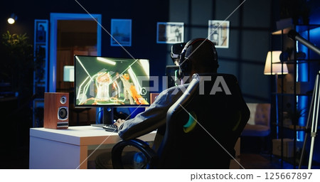 Gamer celebrating winning online multiplayer science fiction videogame tournament, pumping fists in air. Man feeling pleased about gaming championship victory on computer, camera B Gamer celebrating winning online multiplayer science fiction videogame tournament, pumping fists in air. Man feeling pleased about gaming championship victory on computer, camera B 125667897