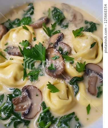 Delicious tortellini pasta in creamy mushroom and spinach sauce garnished with parsley 125668354