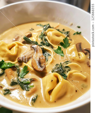 Creamy tortellini soup with mushrooms and parsley in a delicious and savory bowl. 125668355