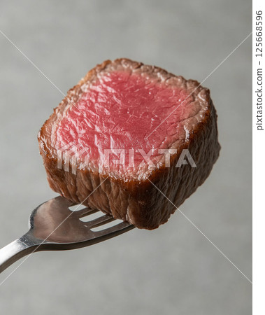 Juicy steak on fork, delicious gourmet beef slice for dinner, grilled to tender perfection 125668596