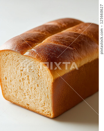 Freshly baked bread loaf with golden crust and soft slice in bakery setting 125668627