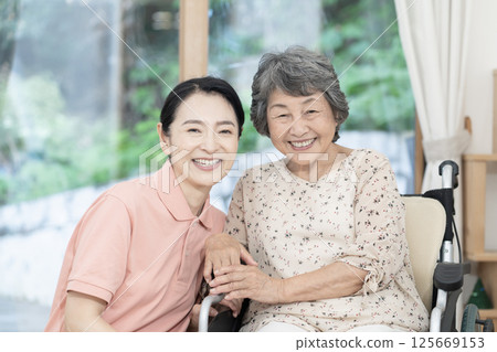Caregiver caring for a senior woman sitting in a wheelchair Caregiver caring for a senior woman sitting in a wheelchair 125669153