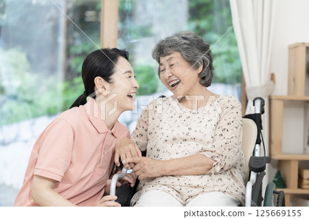 Caregiver caring for a senior woman sitting in a wheelchair Caregiver caring for a senior woman sitting in a wheelchair 125669155