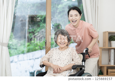 Caregiver caring for a senior woman sitting in a wheelchair 125669157