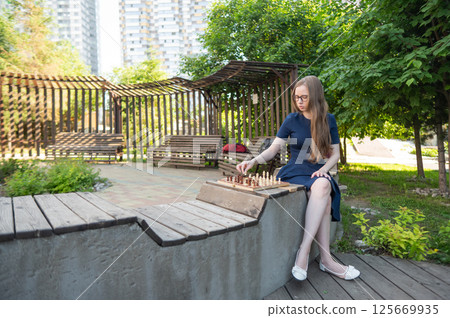 Caucasian woman playing chess outdoors. 125669935