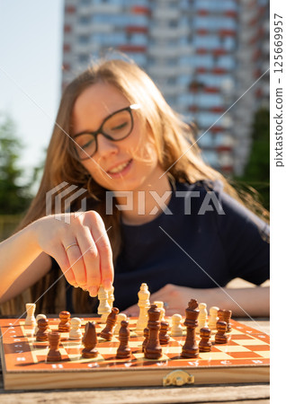 Caucasian woman playing chess outdoors. 125669957