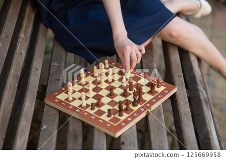 Caucasian woman playing chess outdoors. Caucasian woman playing chess outdoors. 125669958