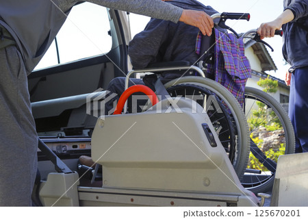 A caregiver putting an elderly person in a care taxi A caregiver putting an elderly person in a care taxi 125670201