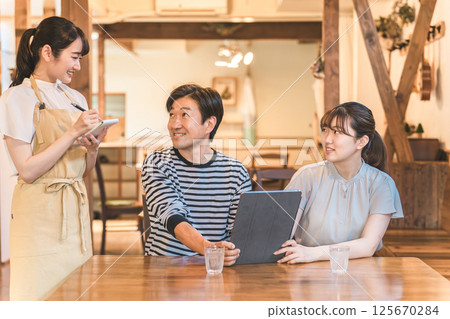 A clerk explaining a man and a woman who order and self-order a menu using a tablet at a cafe, restaurant, or restaurant 125670284