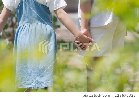 Sisters holding hands in the park Sisters holding hands in the park 125670323