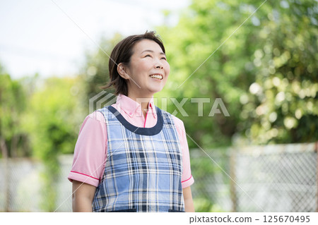 Image of a veteran caregiver or nursery teacher looking up with a smile Image of a veteran caregiver or nursery teacher looking up with a smile 125670495