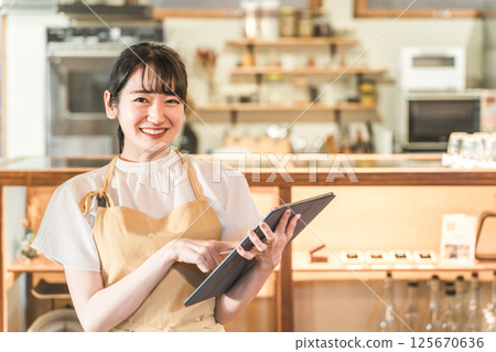 餐廳工作人員(兼職員工、女服務員)在平板電腦上查看訂單 餐廳工作人員(兼職員工、女服務員)在平板電腦上查看訂單 125670636