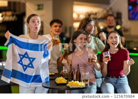 Group of friends cheer together for their favorite Israeli team in beer bar 125670984