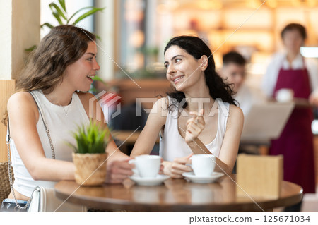 Two women sitting in a coffee shop talking 125671034