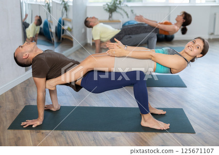Couple yoga practice - man and woman balancing and meditating together in gym 125671107