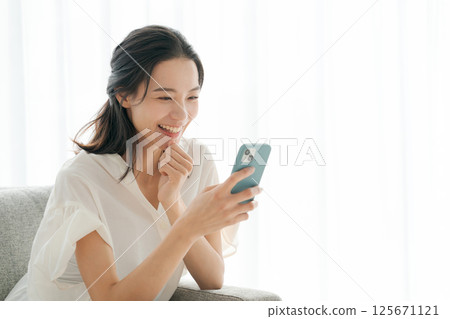 A woman in her 30s operating a smartphone at home 125671121