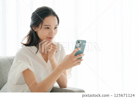 A woman in her 30s operating a smartphone at home A woman in her 30s operating a smartphone at home 125671124
