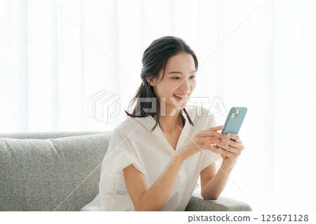A woman in her 30s operating a smartphone at home A woman in her 30s operating a smartphone at home 125671128