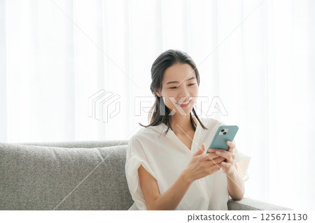 A woman in her 30s operating a smartphone at home A woman in her 30s operating a smartphone at home 125671130