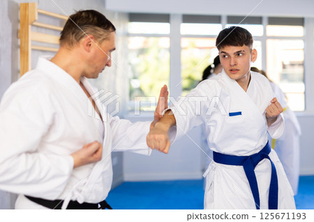 Adult man and young guy training karate techniques Adult man and young guy training karate techniques 125671193