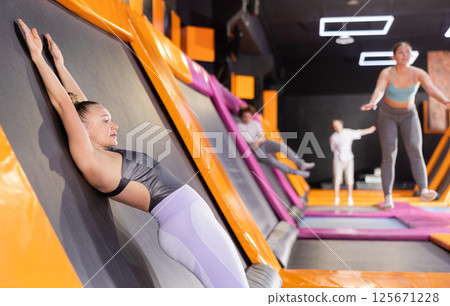 Adult woman trains jumping in trampoline center 125671228