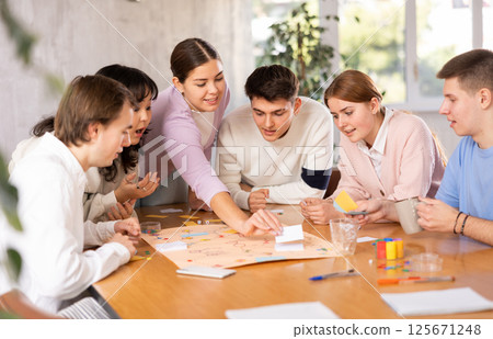 Group of happy young people playing board game 125671248