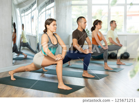 Young woman with multinational group of sporty adult people training stretching workout in yoga studio 125671251
