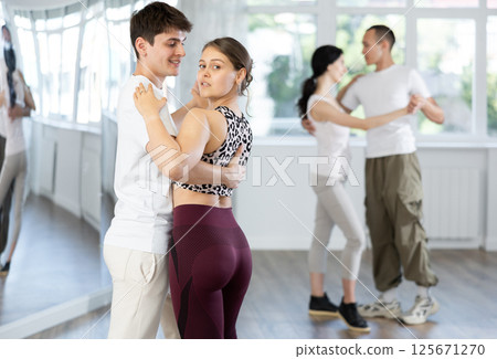 Dance studio - students in casual clothes learn to dance tango Dance studio - students in casual clothes learn to dance tango 125671270
