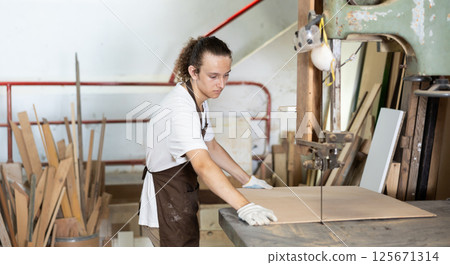 Guy cutting board in taller workshop 125671314