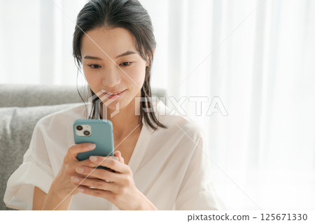 A woman in her 30s operating a smartphone at home A woman in her 30s operating a smartphone at home 125671330