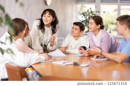 Young female asian teacher giving lecture to group of students Young female asian teacher giving lecture to group of students 125671358